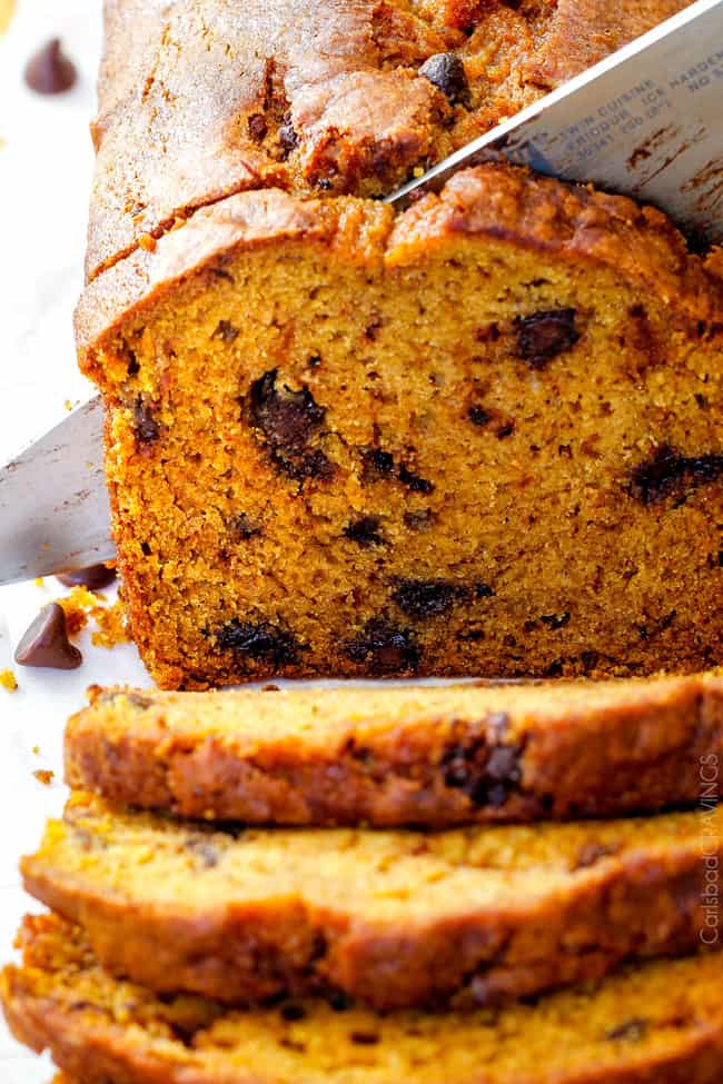 My Momโs Famous Chocolate Chip Pumpkin Bread! So incredibly moist, infused with cinnamon, cloves and nutmeg with only 2 bowls and one whisk required! Everyone will BEG you for this recipe! up close shot of slicing easy pumpkin bread