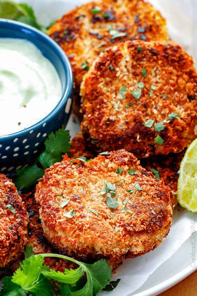 Easy, extra crispy, restaurant quality Crab Cakes right in your own home! Crispy on the outside, moist, juicy, flavor packed on the inside with the BEST DIP ever!! You can also make ahead of time for stress free appetizers! easy crab cakes on a white place stacked on top of each other with crab cake sauce