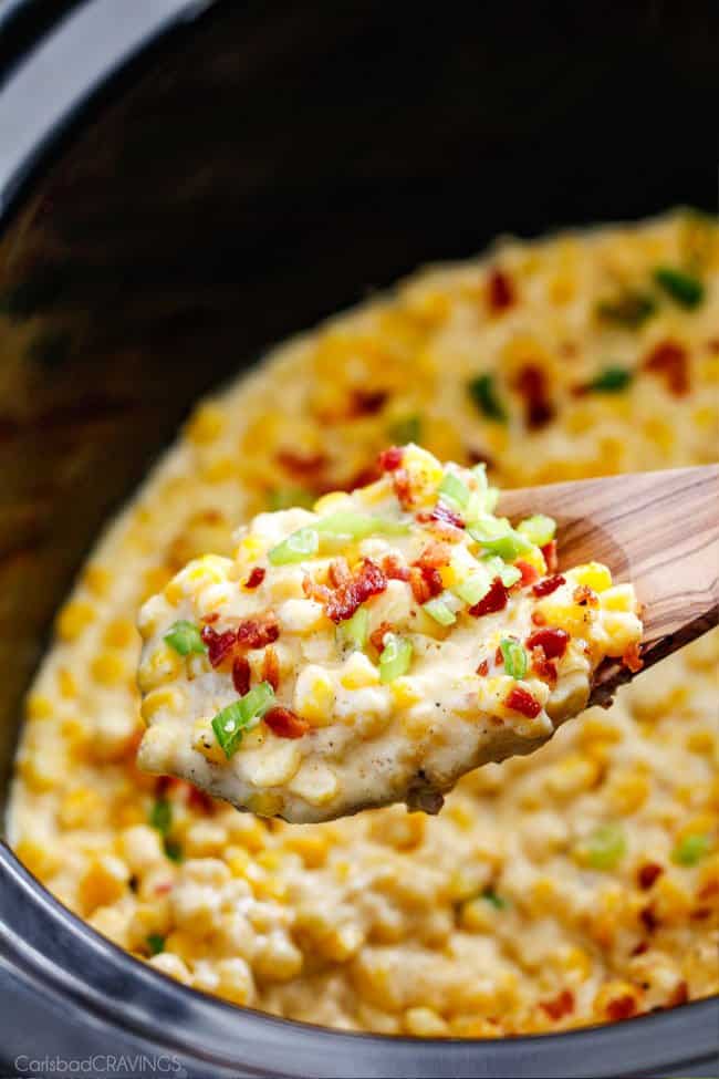 Slow Cooker Creamed Corn with Ricotta and Bacon - this has to be the BEST CREAMED CORN I've eaten in my entire life! Rich and creamy, seasoned to perfection, SO easy and practically fool proof! Definitely making this every Thanksgiving from now on! a serving spoon of southern creamed corn in the slow with green onions and bacon