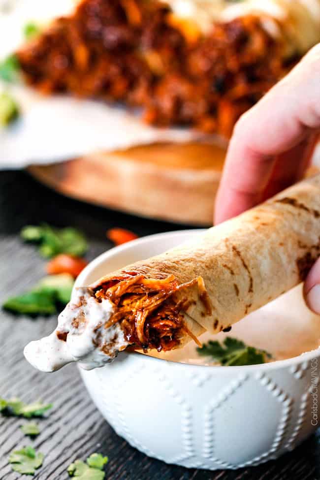 BBQ Pork Taquitos dipped in sauce.