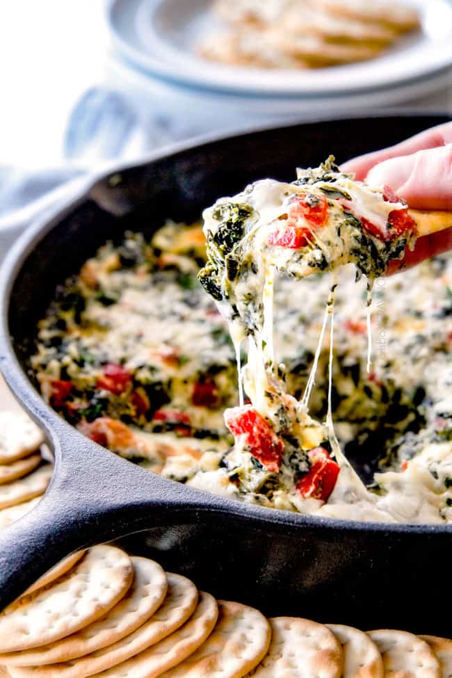 Brie Spinach Dip - my friends could not get over this appetizer! Its your favorite spinach dip made even more delicious with BRIE! Creamy, cheesy and so addicting! pulling cracker away from baked spinach dip with lots of cheese