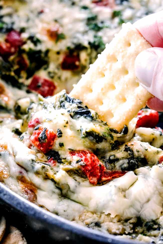 Brie Spinach Dip - my friends could not get over this appetizer! Its your favorite spinach dip made even more delicious with BRIE! Creamy, cheesy and so addicting! up close of a cracker scooping cheesy spinach dip