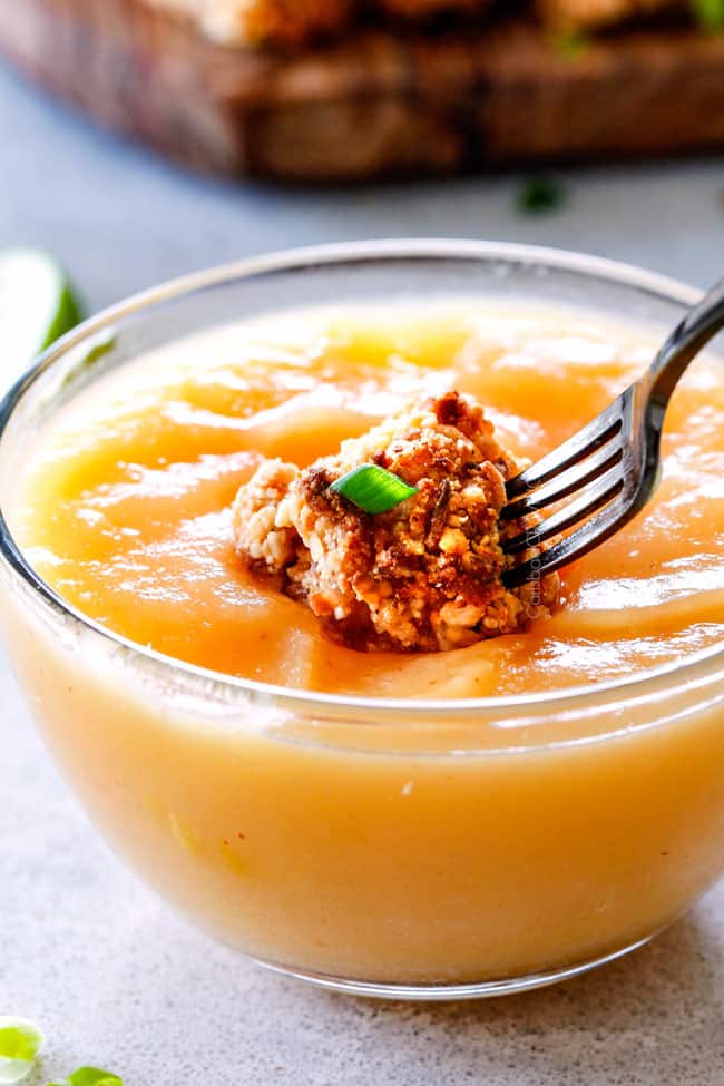 Close up of a Baked Coconut Cashew Chicken Bites being dipped in sauce.