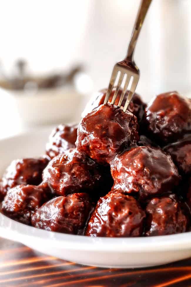 Tender juicy, sweet and spicy Slow cooker Korean Meatballs simmered in the most tantalizing sweet heat sauce that everyone goes crazy for! Perfect appetizer or delicious, easy meal with rice! a plate of crockpot Korean Meatballs with Korean BBQ Sauce with a fork stabbing one of the meatballs