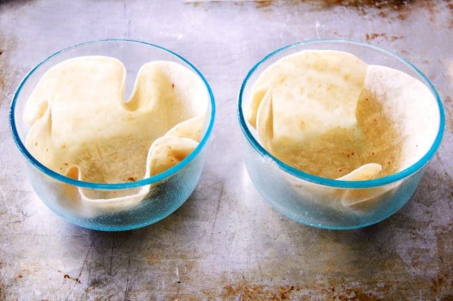 showing how to make tortilla bowls to serve taco salad by placing tortillas inside two glass bowls