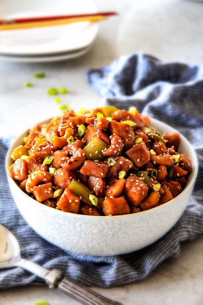 Slow Cooker Chinese Cashew Chicken- this is the best cashew chicken I have ever tried! the chicken is incredibly tender, the sauce is wonderfully flavorful and the punch of buttery, creamy cashews is out of this world! Definitely a family favorite and so much heather than takeout! healthy Cashew Chicken in a white bowl with bell peppers, cashews and sesame seeds