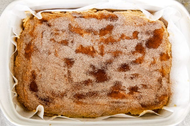 Incredibly EASY, thick, soft and chewy, buttery Snickerdoodle Cookie Bars taste just like the cookie but so much easier and less time consuming! The cinnamon and sugar crackle top is to die for! showing how to make chewy Snickerdoodle bars by topping with cinnamon and sugar