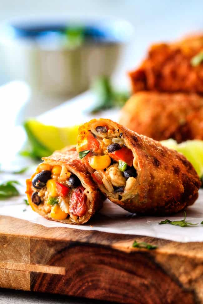 CRISPY Southwest Egg Rolls loaded with Mexican spiced chicken, beans, tomatoes, rice, avocado and cheese! These eggrolls are unreal! So much flavor and texture! And don't skip the Cilantro Lime Ranch Dip - its heaven! crispy southwest egg rolls leaning next to each other filled with chicken, cheese, corn, black beans, tomatoes and avocao