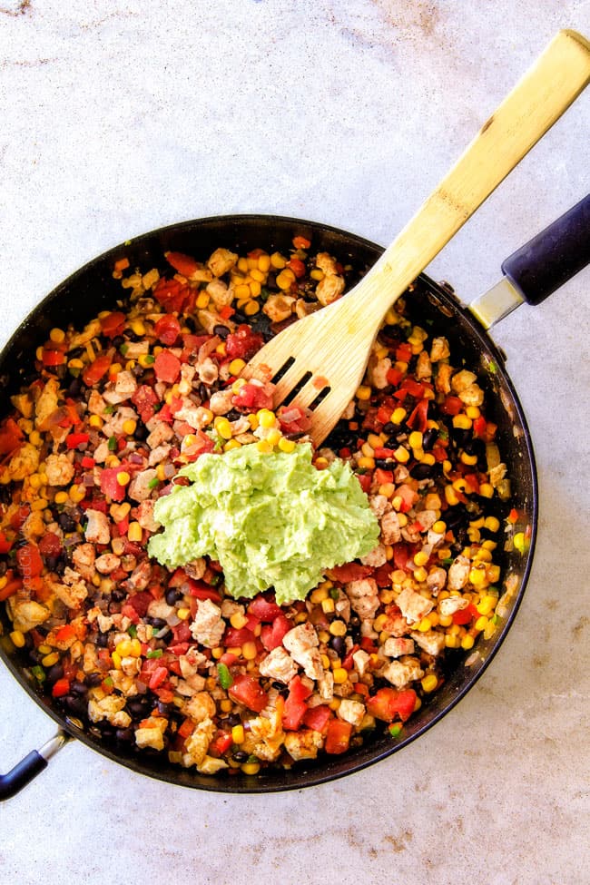 CRISPY Southwest Egg Rolls loaded with Mexican spiced chicken, beans, tomatoes, rice, avocado and cheese! These egg rolls are unreal! So much flavor and texture! And don't skip the Cilantro Lime Ranch Dip - its heaven! Showing how to make Southwest Egg Rolls by adding mashed avocados to filling in a pan