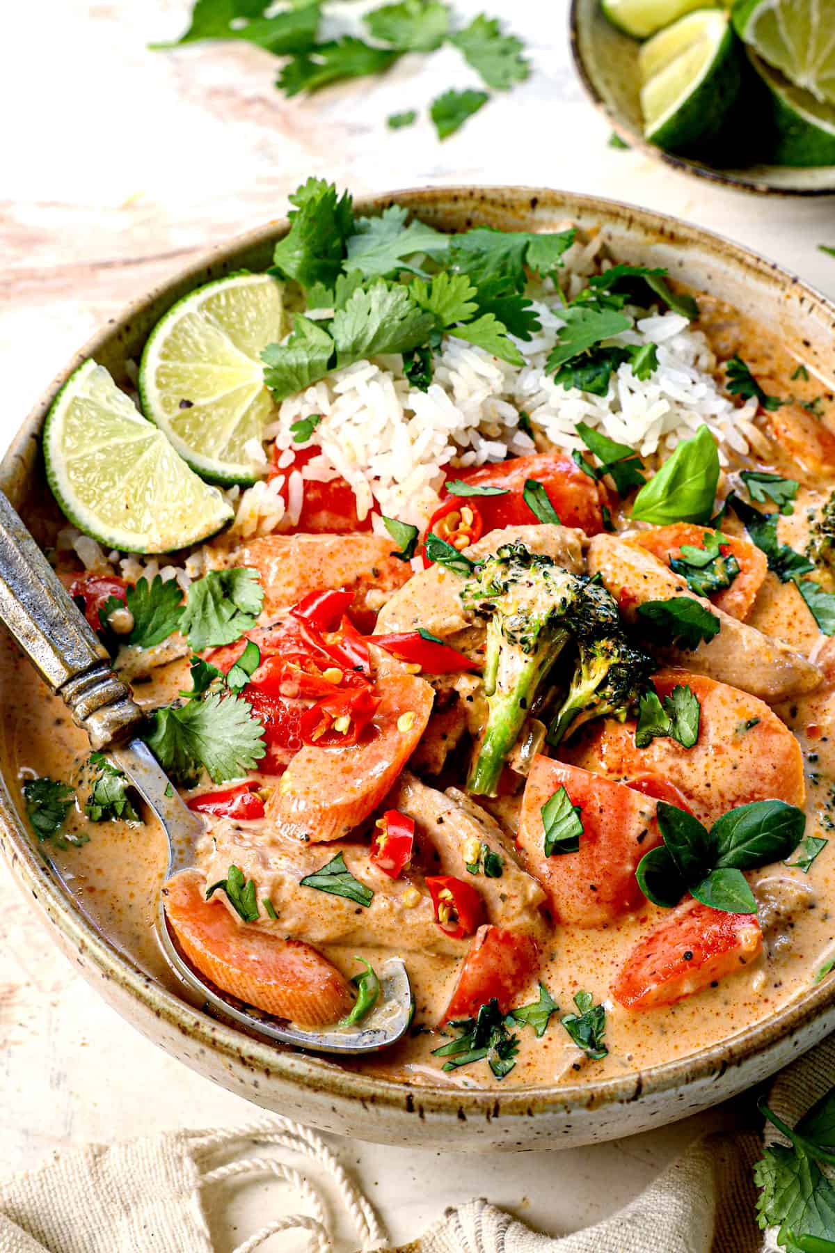 thai curry served in a bowl with rice, garnished by green onions and red chili peppers