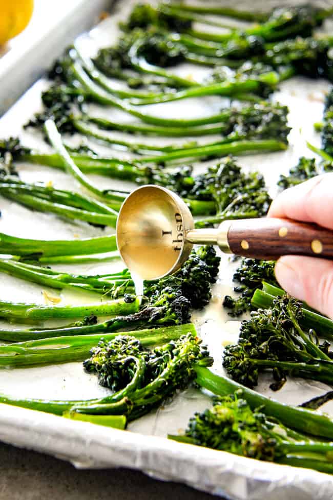 Roasted Parmesan Lemon Garlic Broccoli on a plate with lemon adding butter. .