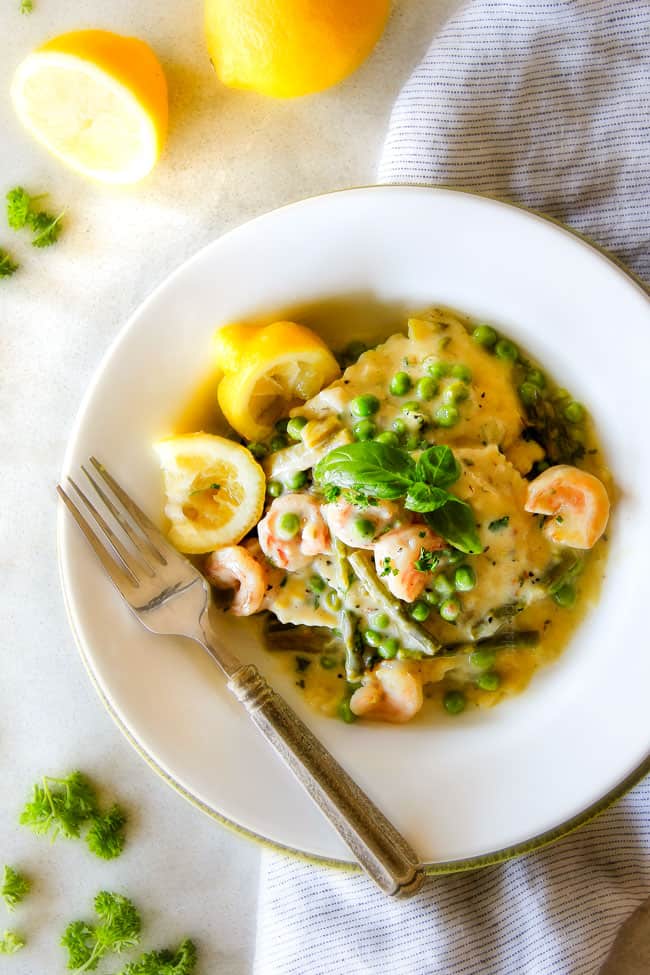 One Pot Lemon Garlic Cream Ravioli with Shrimp and Asparagus on a white plate with a fork.