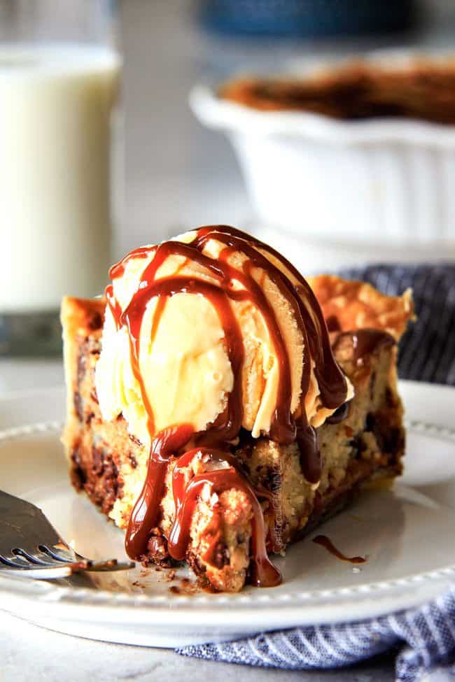 make ahead Million Dollar Cookie Pie layered with Nutella, Dulce de Leche and cookie dough! This is hands down the best skillet cookie I've ever made and its always such a crowd pleaser! a slice of nutella cookie pie on a white plate topped with a scoop of ice cream and chocolate sauce