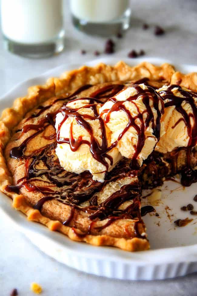 make ahead Million Dollar Cookie Pie layered with Nutella, Dulce de Leche and cookie dough! This is hands down the best skillet cookie I've ever made and its always such a crowd pleaser! deep dish chocolate chip cookie pie in a white pie pan topped with ice cream with a few slices missing
