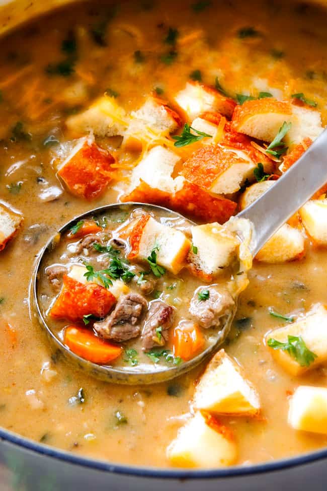 A scoop of Philly Cheesesteak Soup in a serving spoon.