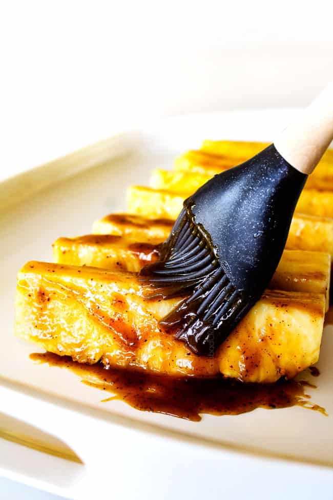 the BEST Caramelized Grilled Pineapple glazed with the moist irresistible buttery, tangy Brown Sugar Chili Glaze! You will never want to eat pineapple any other way again! Serve it as an easy appetizer, side or even dessert all summer long! showing how to make Grilled Pineapple by brushing pineapple with glaze