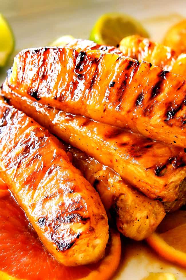 the BEST Caramelized Grilled Pineapple smothered with the moist irresistible buttery, sweet, tangy Brown Sugar Orange Glaze! You will never want to eat pineapple any other way again! Serve it as an easy appetizer, side or even dessert all summer long! up close of healthy grilled pineapple in a pile on a platter