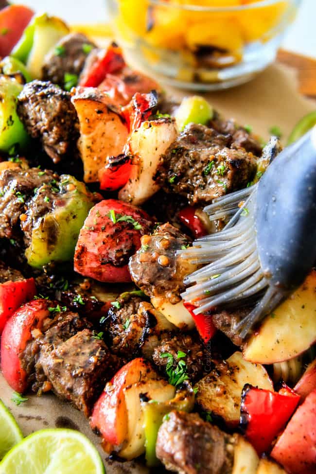 Brazilian Steak Kabobs brushing the steak.