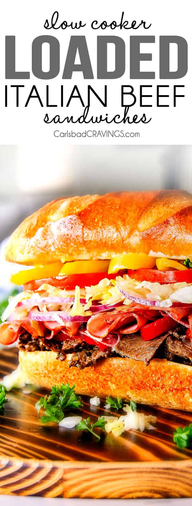 Easy, customizable LOADED Slow Cooker Italian Beef Sandwiches are crazy tender, seeping with flavor and unbelievably delicious! They make the easiest dinner or party food and super fun (make ahead!) sandwich bar! ย quick italian beef sandwich recipe with a fully loaded Italian beef sandwich on a cutting board