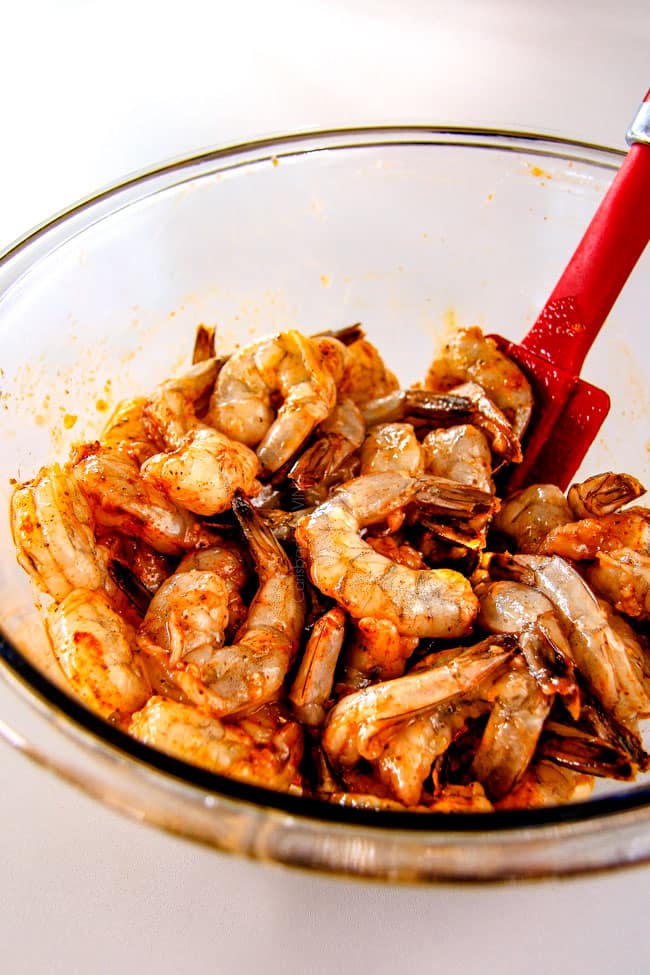 showing how to make Old Bay Shrimp by mixing shrimp with seasonings in a bowl