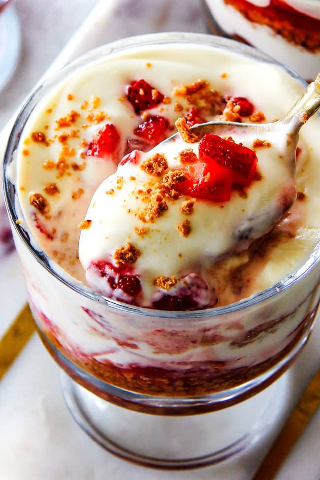 Top view of Strawberry Cheesecake Parfaits with a spoon taking a scoop off the top.