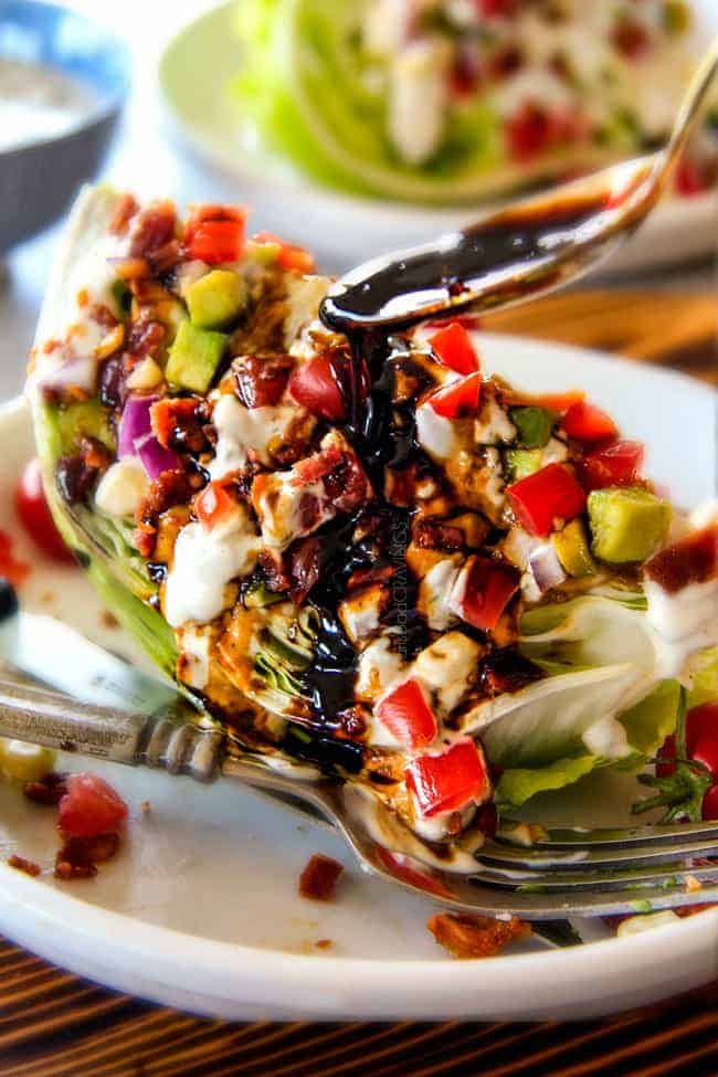 Outback Copycat Wedge Salad smothered in the most amazing creamy, decadent Blue Cheese Ranch and Balsamic Reduction is a flavor/texture lovers dream and crazy easy to make! ย showing how to eat wedge salad by smothering it with dressing