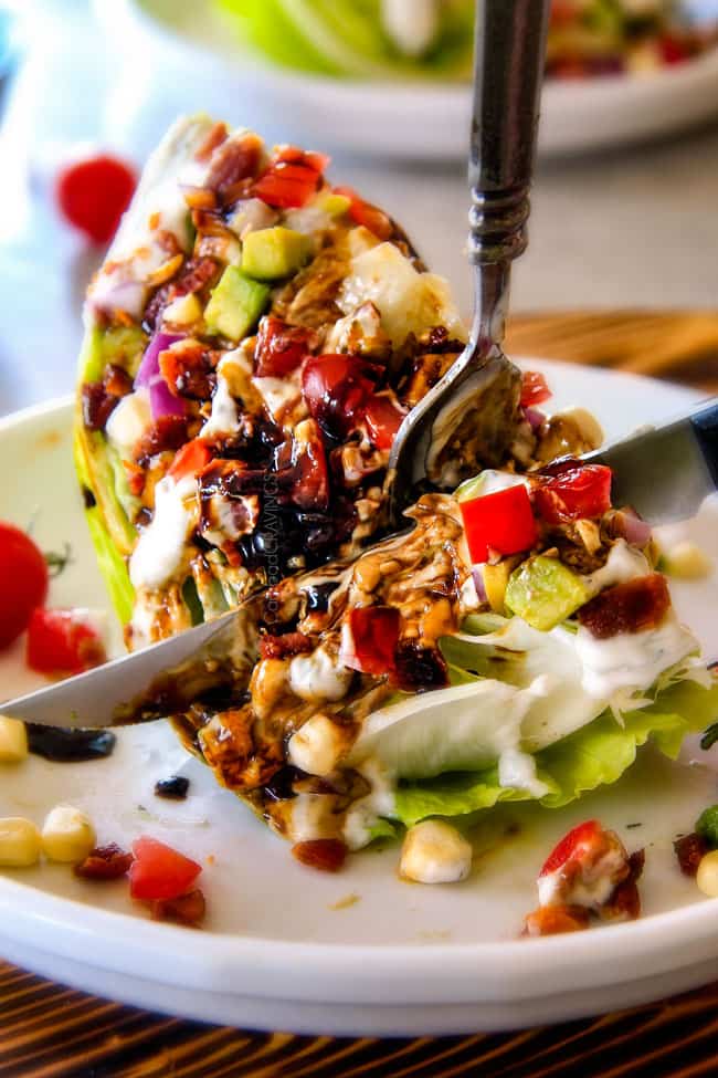 Outback Copycat Wedge Salad smothered in the most amazing creamy, decadent Blue Cheese Ranch and Balsamic Reduction is a flavor/texture lovers dream and crazy easy to make! ย showing how to eat Wedge Salad by cutting it with a knife and fork