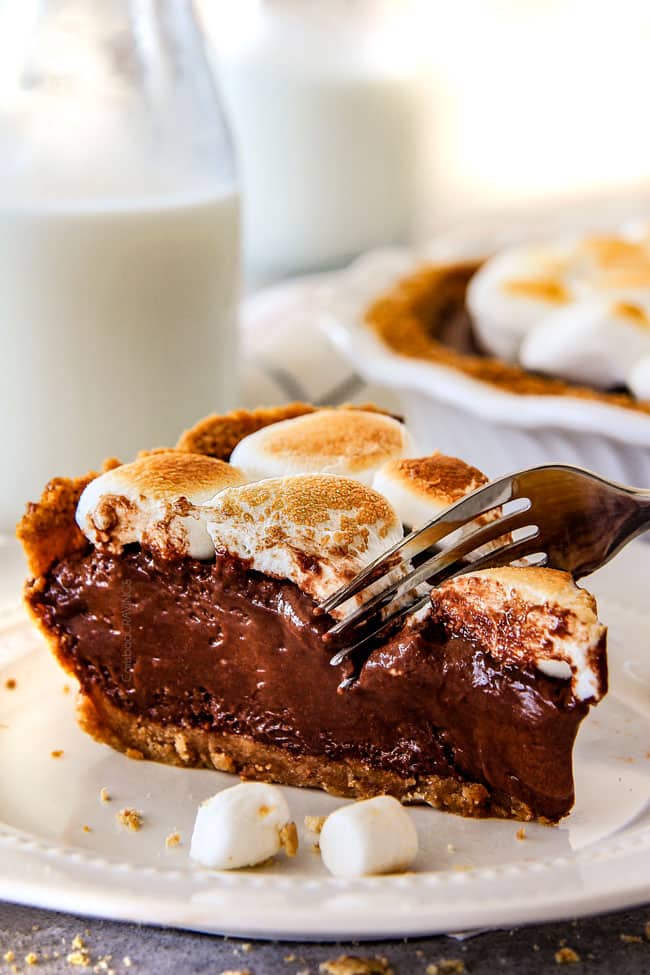 Cutting into a Nutella S'mores Pie with marshmallow on top.