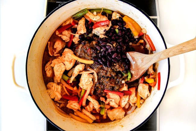 Lighter ONE POT Chicken Fajita Pastaย has only minutes of hands-on cooking time! ย Its smothered in cheesy, creamy salsa infused sauce bursting with your favorite fajita spiced chicken, onions and peppers! ย The pasta cooks right IN the sauce for simple prep, minimal cleanup, and extra flavooooor! ย showing how to make easy chicken fajita pasta by adding black beans to chicken, bell peppers and onions