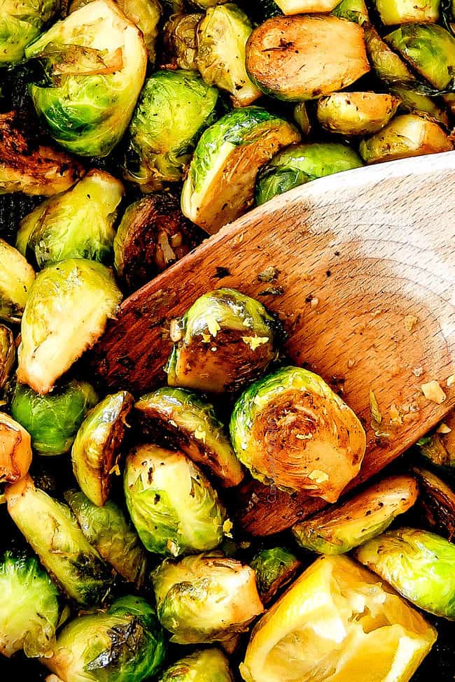 top up close of crispy Sautéed Brussels Sprouts in a skillet with a wooden spoon