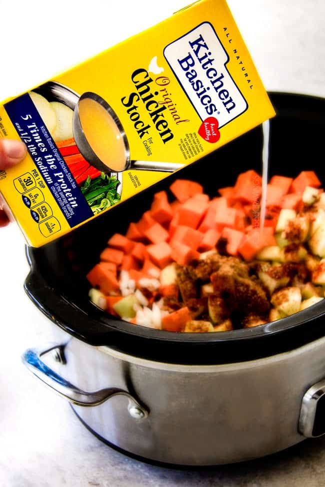 this SUPER creamy Slow Cooker Chipotle Sweet Potato Soup is AMAZING!ย Its loaded with flavor, gluten free, dairy free, crazy healthy and so easy!ย Definitely one of my new favorite soups!ย ย showing how to make Sweet Potato Soup by pouring chicken broth into the pot with sweet potatoes and spices