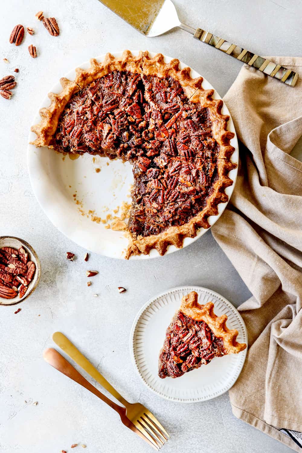 top view of homemade pecan pie with a few slices missing and a slice of pie on a plate