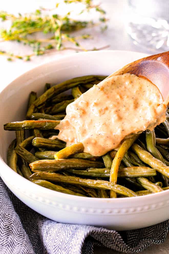 Forget green bean casserole, these wonderfully flavorful, crisp tender Roasted Green Beans with Creamy Gruyere Sauce are AMAZING!!!ย They the best green beans you will ever eat!ย ย They are easy enough for every day but delicious enough for special occasions (like Thanksgiving, Christmas!)!ย showing how to make roasted green beans by adding cheese sauce