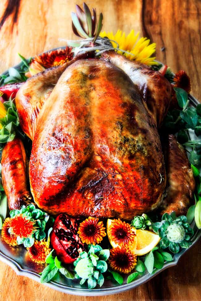 Roast Turkey with Herb Butter on a platter with flowers.