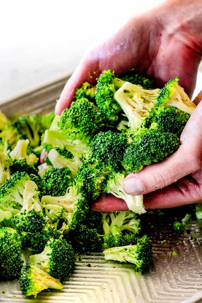 QUICK AND EASY this Parmesan Roasted Broccoli is bursting with flavor, caramelized crispy tops and the quickest side dish to everyย meal all made in ONE PAN!ย AKA Minimal effort, HUGE flavor! showing how to roast broccoli by tossing broccoli with olive oil on a baking sheete