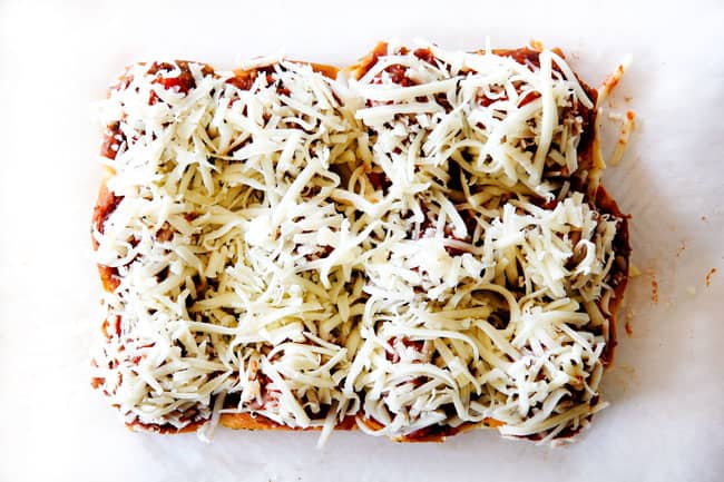 These Cheesy Italian Meatball Sliders are my favorite party food ever and my family loves them for dinner!ย The meatballs are the BEST (so tender and juicy!) and the marinara is amazing and I love how they are individual sliders instead of meatball subs!ย I can't recommend these enough!ย showing how to make meatball sliders by topping meatballs with cheese