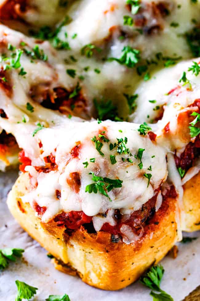 These Cheesy Italian Meatball Sliders are my favorite party food ever and my family loves them for dinner!ย The meatballs are the BEST (so tender and juicy!) and the marinara is amazing and I love how they are individual sliders instead of meatball subs!ย I can't recommend these enough!ย top up close view of best meatball slider on a Hawaiian roll