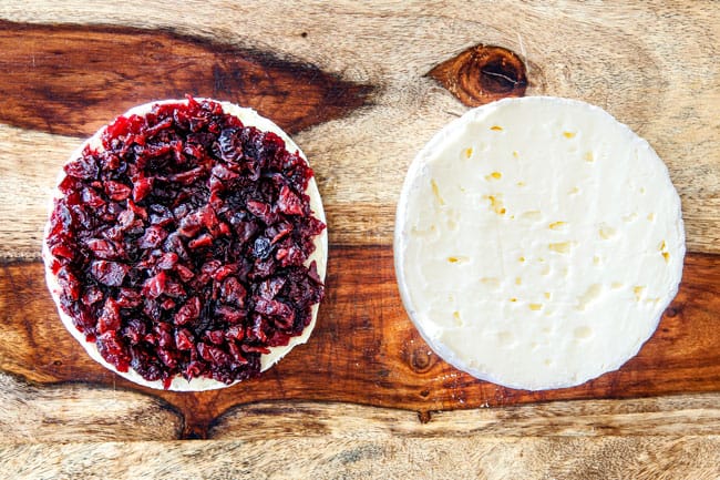 Rich and creamy Baked Brie in Puff Pastry is always a total luxuriously tasting crowd pleaser with minimal effort!ย (step by step pictures included)ย It can be prepped in advance then baked when you're ready for company!ย aaaaaaaaa showing how to make baked brie in puff pastry by adding jam and cranberries to one half of brie