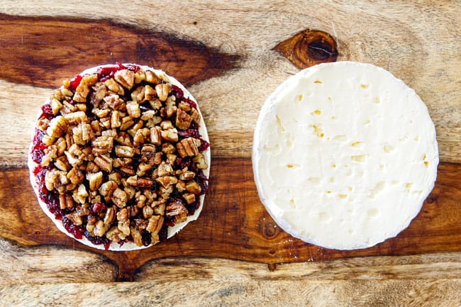 Rich and creamy Baked Brie in Puff Pastry is always a total luxuriously tasting crowd pleaser with minimal effort!ย (step by step pictures included)ย It can be prepped in advance then baked when you're ready for company!ย aaaaaaaaa showing how to make baked brie in puff pastry by adding pecans to top of jam