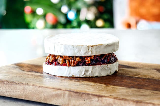 Rich and creamy Baked Brie in Puff Pastry is always a total luxuriously tasting crowd pleaser with minimal effort!ย (step by step pictures included)ย It can be prepped in advance then baked when you're ready for company!ย aaaaaaaaa showing how to make baked brie in puff pastry by assembling top and bottom of brie with jam filling in the middle