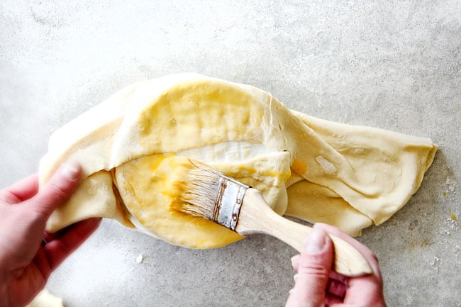 Rich and creamy Baked Brie in Puff Pastry is always a total luxuriously tasting crowd pleaser with minimal effort!ย (step by step pictures included)ย It can be prepped in advance then baked when you're ready for company!ย showing how to fold baked brie in puff pastry