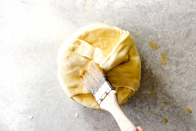 Rich and creamy Baked Brie in Puff Pastry is always a total luxuriously tasting crowd pleaser with minimal effort!ย (step by step pictures included)ย It can be prepped in advance then baked when you're ready for company!ย brushing baked brie in puff pastry with egg wash