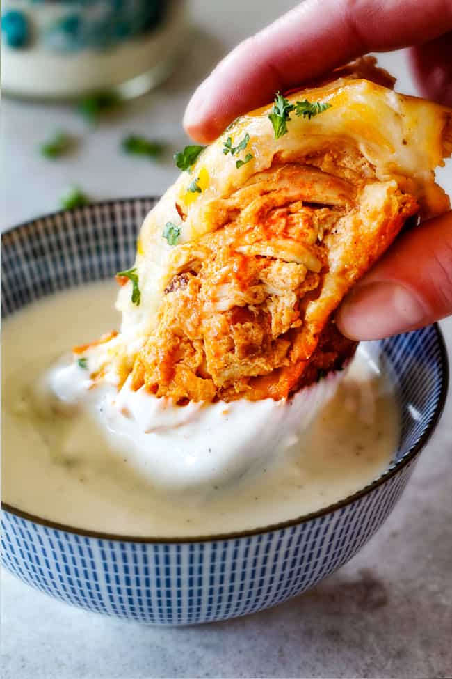 Mega flavorful Buffalo Chicken Pull Apart Bread is your favorite decadent creamy, cheesy dip baked right into a buttery biscuit ring! Crazy delicious EASY crowd pleasing appetizer perfect for parties or game day!ย ย It may look super impressive but you wonโt believe how easy it is! up close of Buffalo Chicken Pull Apart Bread in a bowl of ranch
