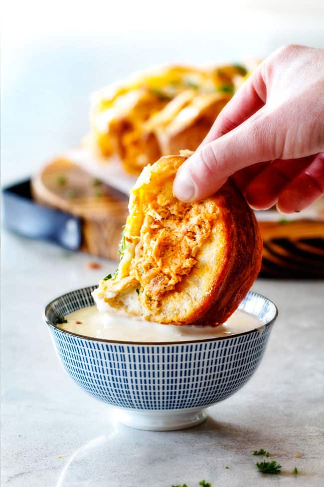 Mega flavorful Buffalo Chicken Pull Apart Bread is your favorite decadent creamy, cheesy dip baked right into a buttery biscuit ring! Crazy delicious EASY crowd pleasing appetizer perfect for parties or game day!ย ย It may look super impressive but you wonโt believe how easy it is! dipping a piece of Buffalo Chicken Pull Apart Bread in blue cheese dressing