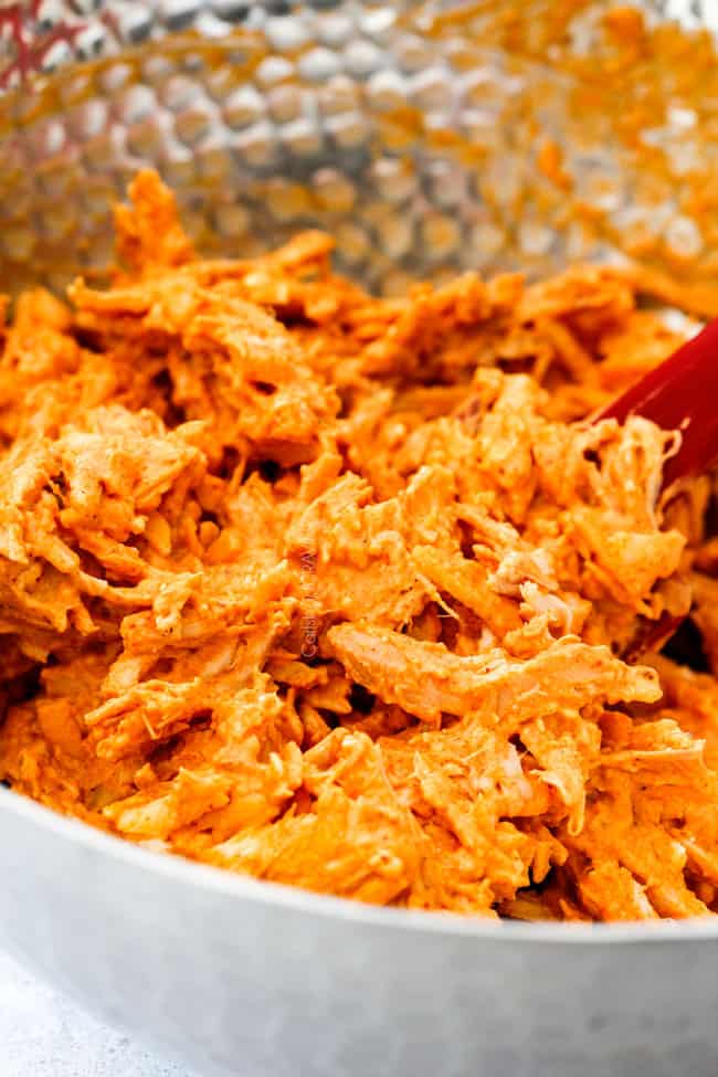 Mega flavorful Buffalo Chicken Pull Apart Bread is your favorite decadent creamy, cheesy dip baked right into a buttery biscuit ring! Crazy delicious EASY crowd pleasing appetizer perfect for parties or game day!ย ย It may look super impressive but you wonโt believe how easy it is! showing how to make Buffalo Chicken Pull Apart Bread by mixing buffalo chicken, cream cheese and bacon together