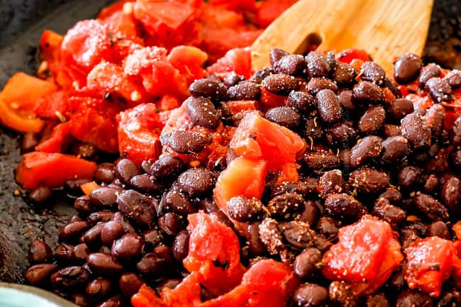 Mixing beand and tomatoes to make Cajun Chicken Black Bean Bowls with Avocado, Sweet Potatoes & Pineapple.