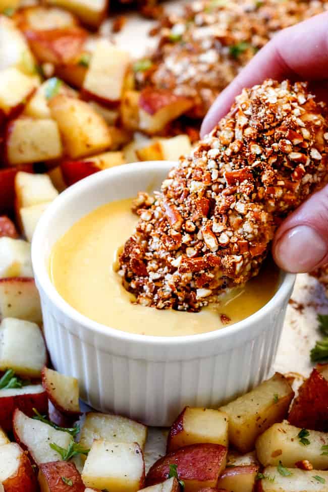 Dipping Sheet Pan Honey Mustard Pretzel Chicken & Potatoes in sauce.