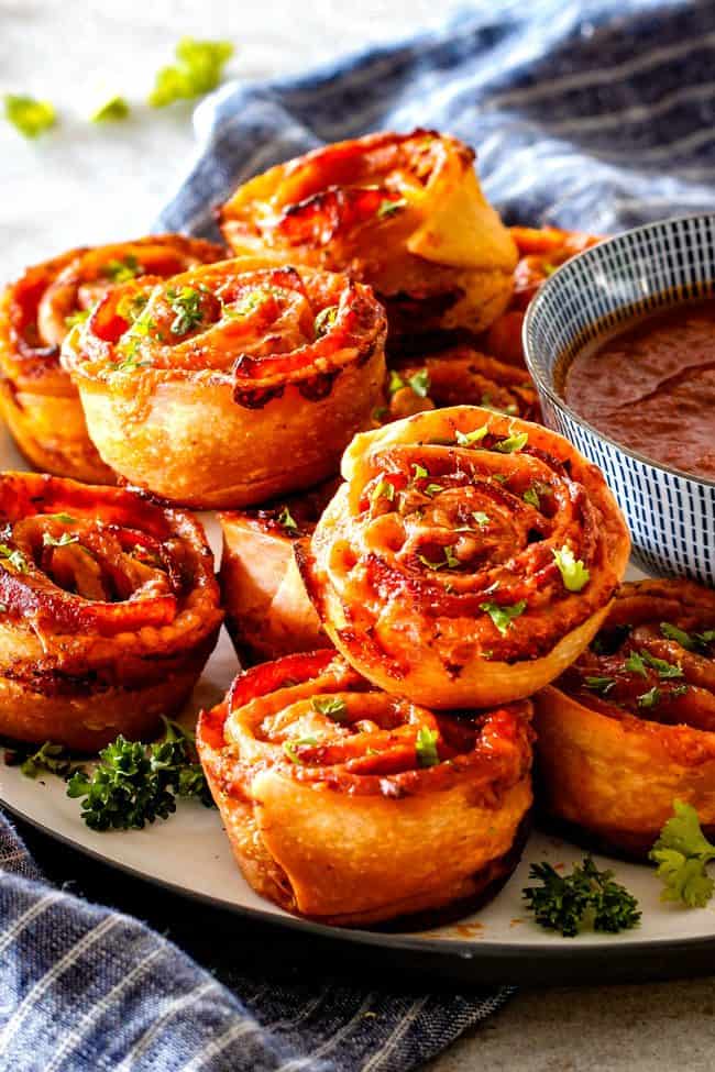 These Pizza Pinwheels are super easy to make, customizable, freeze beautifully, and absolutely irresistible for snacks, appetizers or fun meals! You friends and family will beg you to make these! pizza pinwheels on a plate with marinara sauce