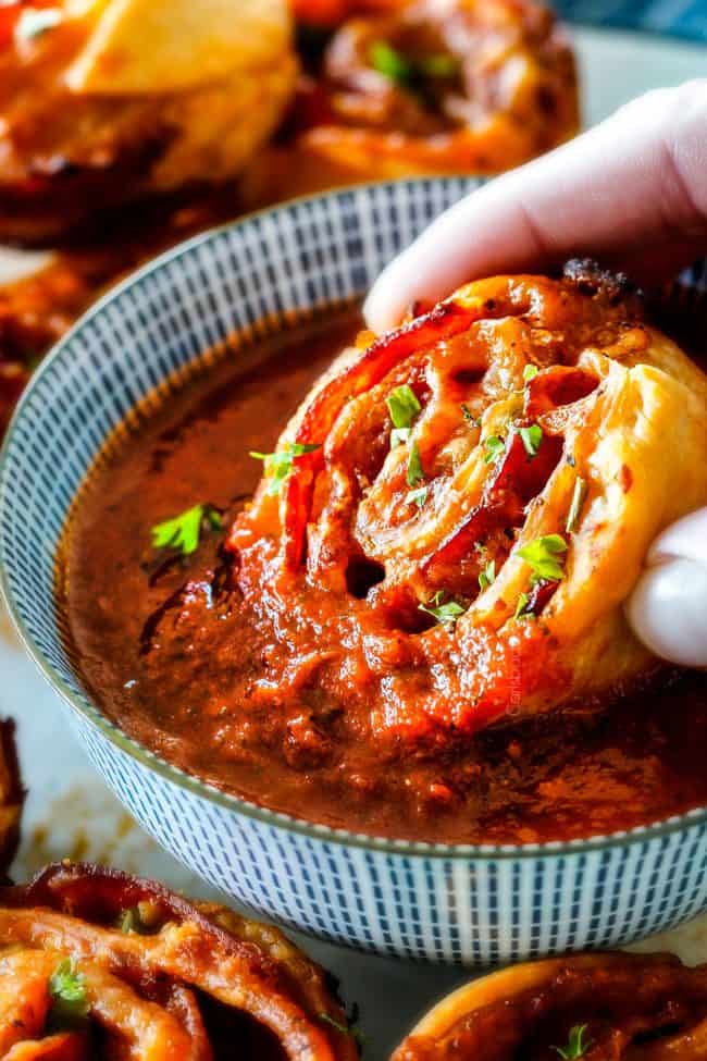 These Pizza Pinwheels are super easy to make, customizable, freeze beautifully, and absolutely irresistible for snacks, appetizers or fun meals! You friends and family will beg you to make these! dunking a Pizza Pinwheel in pizza sauce