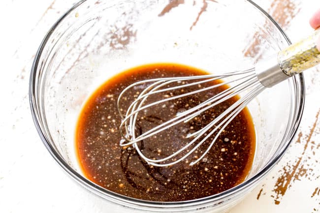 marinade in a glass bowl with a wire whisk showing how to make beef and broccoli